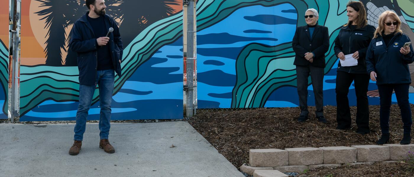 Local artist Stiles-Mikl with the vibrant mural he created behind him.