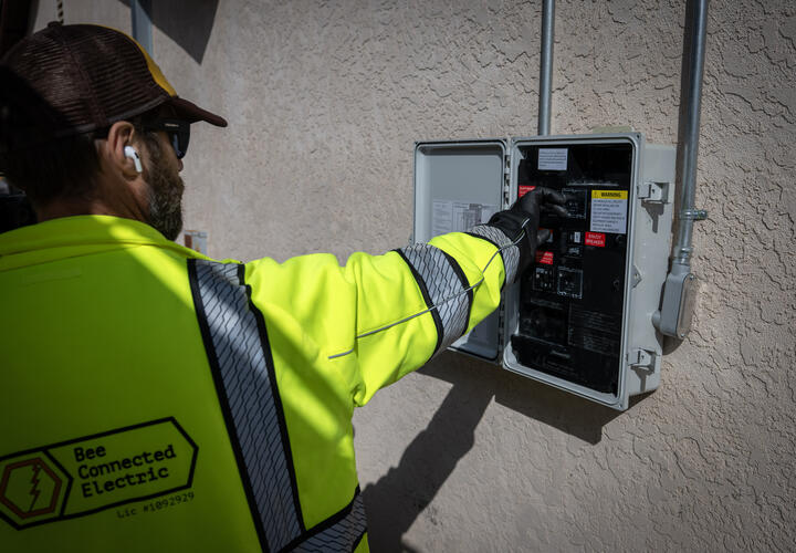 A male electrician adjusts a switch in a solar electric box.