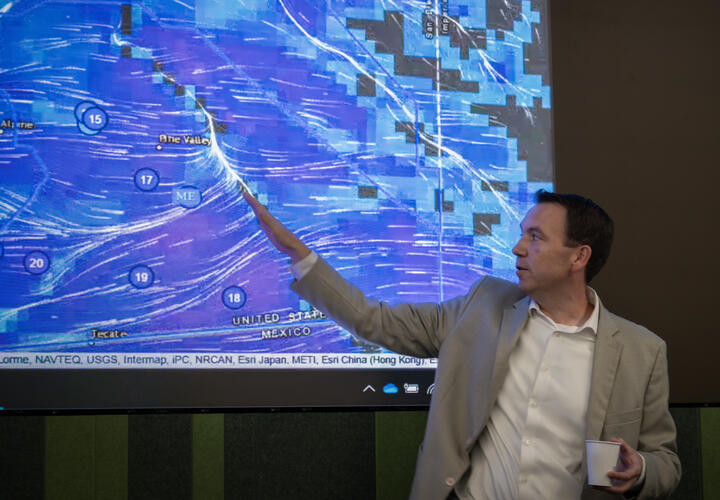 SDG&E's Brian D’Agostino, vice president Of Wildfire and Climate Science, points at a large screen featuring weather data.