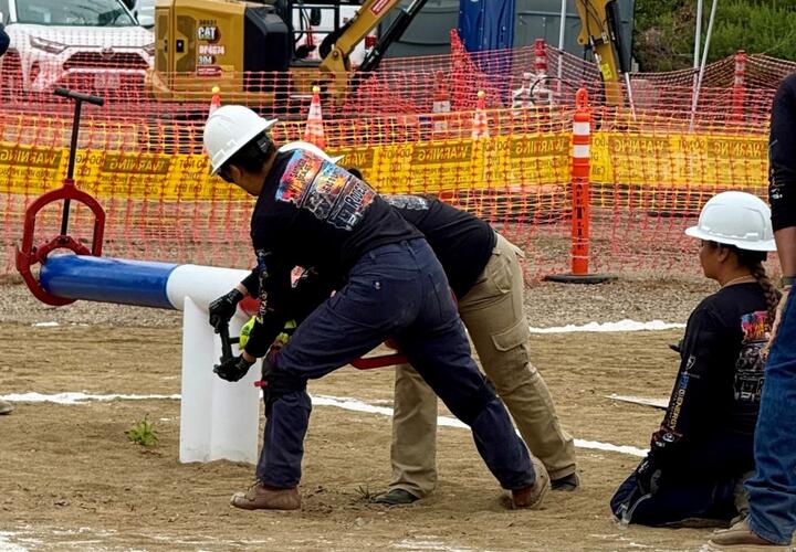 Three women wearing SDG&E hard hats participate in the lineworker rodeo.