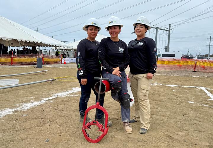 Noelya Collon, Maria Diaz-Gomez, and Ernie Guerrero pose for a photo wearing SDG&E hard hats.