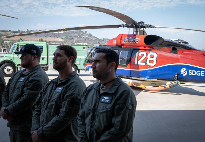 Members of regional public safety agencies with an SDG&E helicopter in the background.