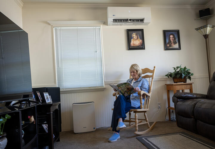 a women reads while sitting in a rocking chair inside a living room