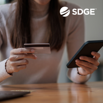 A photo of a woman holding her mobile phone in one hand, and a credit card in the other. 