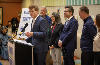 Former Congressman and President of Citizens Energy, Joe Kennedy III standing at a podium announcing the donation of EVs to three San Diego County non-profits. 