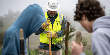 Students and an SDG&E Arborist dig during a tree planting event at Julian Junior High School.