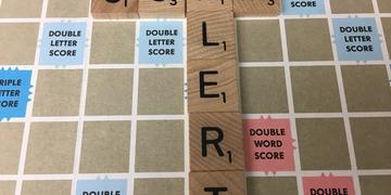 Scam alert image spelled out in Scrabble tiles