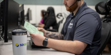 Male customer service representative reviews document at a computer workstation