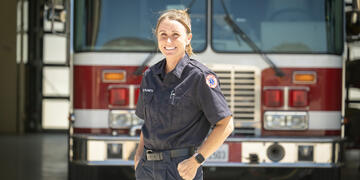 Female fire cadet poses in front of fire engine