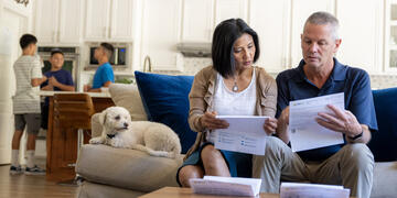 A man and a woman sitting on a couch in their home, reviewing their energy bill.