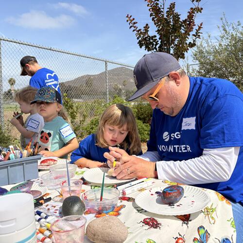 An SDG&E volunteer paints rocks with his daughter.
