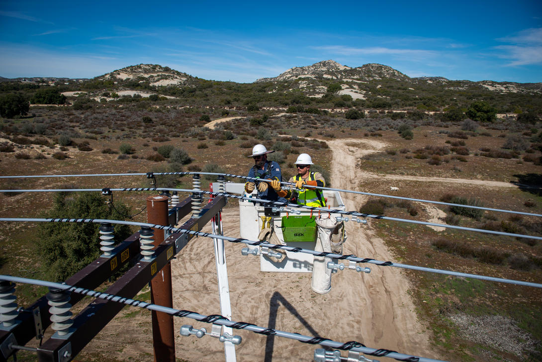 Two linemen in a bucket truck repairing power lines. 